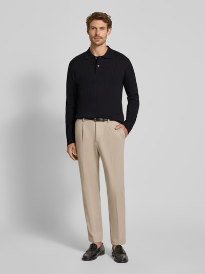Männermodel trägt Regular Fit Poloshirt aus reiner Baumwolle Modell 'TORINO' von Selected in Schwarz, Beigehose, Ganzkörperansicht von vorne.