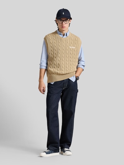 Męski model nosi Regular Fit Pullunder aus reiner Baumwolle von Polo Ralph Lauren, beżowy, faktura warkoczowa, regularny krój, napis z logo, dekolt okrągły, dzianina z bawełny, widok całej sylwetki z przodu.