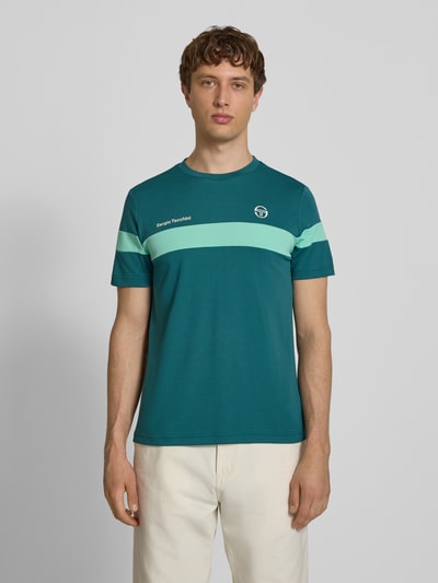 Männermodel trägt Regular Fit T-Shirt mit Logo-Print Modell 'Leone' von SERGIO TACCHINI in Türkis mit Rundhalsausschnitt, Ganzkörperansicht von vorne, Herren T-Shirt, Rückenlänge bei Größe M 71 cm.