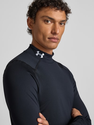 Männermodel trägt Longsleeve mit Stehkragen von Under Armour in Schwarz, Material-Mix mit Stretch, Slim Fit, Nahaufnahme Oberkörper.