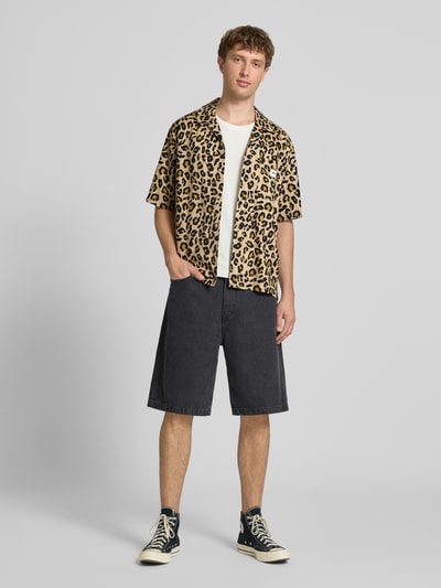 Männermodel trägt Relaxed Fit Freizeithemd aus reiner Baumwolle Modell 'ZEKE' von Only & Sons, beige mit schwarzem Leopardenmuster, Ganzkörperansicht von vorne.