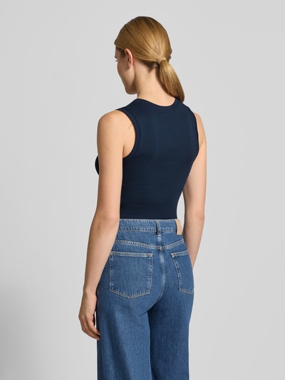 Frauenmodel trägt Slim Fit Tank Top aus reiner Baumwolle Modell 'SLIM CODY' von Tommy Hilfiger in Dunkelblau, unifarben, Logo-Stitching, Ganzkörperansicht Rückansicht.