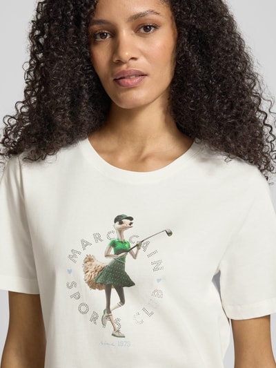 Frauenmodel trägt Regular Fit T-Shirt mit Ziersteinbesatz von Marc Cain, reine Baumwolle, Rundhalsausschnitt, Motiv-Print, Nahaufnahme Oberkörper.