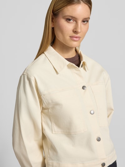 Vrouwenmodel draagt Regular Fit jack met borstzakken model 'Bess' van Soyaconcept in beige katoenmix, platte kraag, knoopsluiting. Close-up bovenlichaam. Context: dames jack van Soyaconcept, elastische katoenmix, regular fit, model 'Bess', borstzakken, platte kraag, doorlopende knoopsluiting, ruglengte bij maat S: 54 cm, schouderbreedte bij maat S: 48 cm, borstwijdte bij maat S: 50 cm, mouwlengte bij maat S: 56 cm.