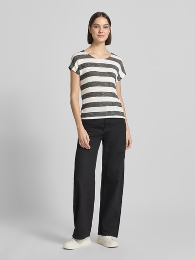 Frauenmodel trägt Regular Fit T-Shirt aus Viskose-Mix Modell 'WIDE STRIPE' von Vero Moda mit Streifen-Design, Mehrfarbig, Label-Stitching-Applikation, U-Boot-Ausschnitt, Kurzarm, abgerundet, Asymmetrisch, Feinstrick Materialverarbeitung, Ganzkörperansicht von vorne.