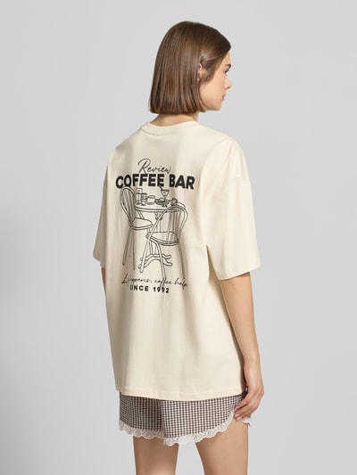 Frauenmodel trägt Oversized T-Shirt mit Statement-Print von REVIEW aus reiner Baumwolle, Oversize Fit, Rundhalsausschnitt, Rückenlänge bei Größe S 70 cm, Ganzkörperansicht Rückansicht.