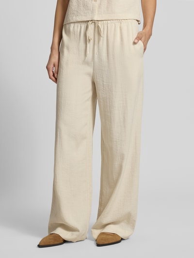 Frauenmodel trägt Straight Fit Hose aus Viskose-Mix Modell 'Daria' von MSCH Copenhagen, Leinen-Viskose-Anteil, crèmefarben, Tunnelzugbund, strukturierte Textur, Nahaufnahme Oberkörper bis Füße.