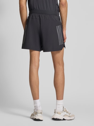 Männermodel trägt Regular Fit Sport-Shorts mit Logo-Print von adidas Training, Optik: Unifarben, Bundabschluss: elastisch, Ganzkörperansicht Rückansicht.