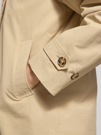 Frauenmodel trägt Jacke mit Eingrifftaschen und Ärmelriegeln von Gant in Beige, glatte Textur, Detailaufnahme Ärmel und Tasche, Baumwoll-Mix, Regular Fit, Knopfverschluss.