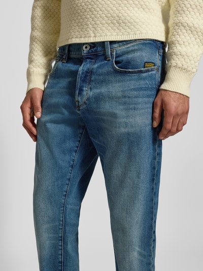Männermodel trägt Regular Tapered Fit Jeans im Used Look Modell '3301' von G-Star, blaue Waschung, Baumwoll-Elasthan-Mix, Eingrifftaschen, Nahaufnahme Oberkörper. Bundweite 43 cm, Innenbeinlänge 79 cm.