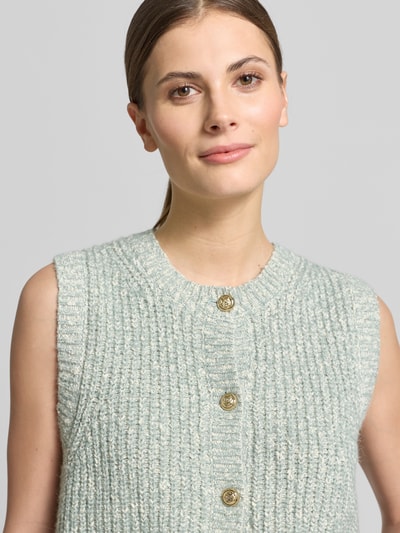 Frauenmodel trägt Strickweste Melange Effekt mit Schmuckknopf von Christian Berg Woman, Baumwoll-Mix, Nahaufnahme Oberkörper.
