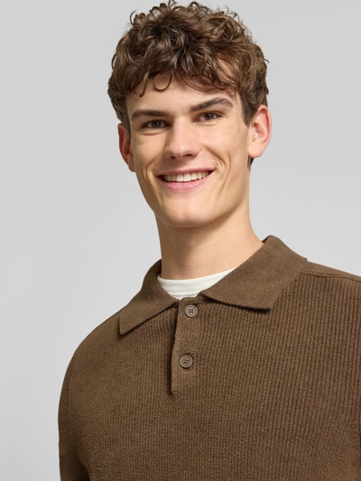 Męski model nosi Regular Fit Strickpullover mit Polokragen od Marc O'Polo Denim, jednolity brązowy sweter z długim rękawem, rippstrick; zbliżenie na górną część ciała.