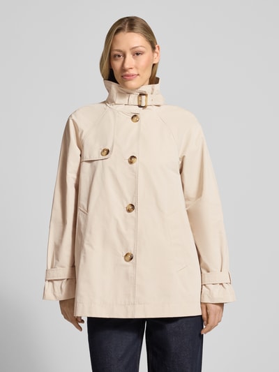 Vrouwenmodel draagt Trenchcoat mit Stehkragen und Ärmelriegeln van Fuchs Schmitt in beige, regular fit, knoopsluiting, zijzakken, detailopname bovenlichaam, voorkant.