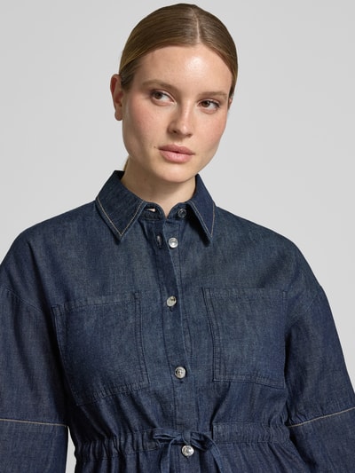 Frauenmodel trägt Hemdbluse in Denim-Optik mit Brusttaschen von Comma, reine Baumwolle, taillierte Passform, Halbarm, Nahaufnahme Oberkörper.