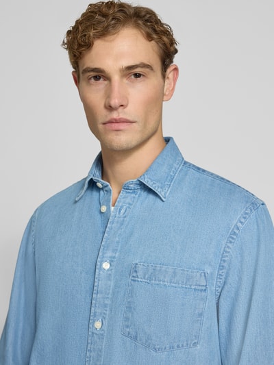 Męski model nosi jasnoniebieską koszulę casualową Regular Fit Freizeithemd aus reiner Baumwolle model 'REGCARLO' od Selected, tekstura gładka, z przodu kieszeń, koniec kołnierza widoczny, kolor jednolity, kontekst: Herren Freizeithemd von Selected, zbliżenie na górną część ciała.