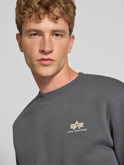 Männermodel trägt Sweatshirt mit Label-Details von Alpha Industries, Baumwoll-Mix, gerader Schnitt, Nahaufnahme Oberkörper.