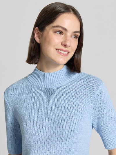 Frauenmodel trägt Strickpullover mit 1/2-Arm Modell 'Tavery Detail' von Someday aus Baumwoll-Mix in Hellblau, Nahaufnahme Oberkörper. Regular-Fit, Stehkragen, Rückenlänge 50 cm, Ärmellänge 28 cm bei Größe 36.