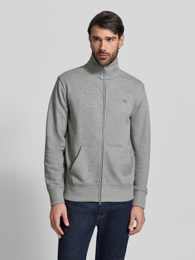 Männermodel trägt Regular Fit Sweatjacke mit Stehkragen Modell 'Gield' von Gant in Grau, Baumwoll-Mix, Logo-Stitching, Ganzkörperansicht von vorne.