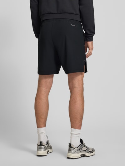 Männermodel trägt schwarze Shorts mit Logo und elastischem Bund von EA7 Emporio Armani, Material-Mix, Regular Fit, Ganzkörperansicht Rückansicht.