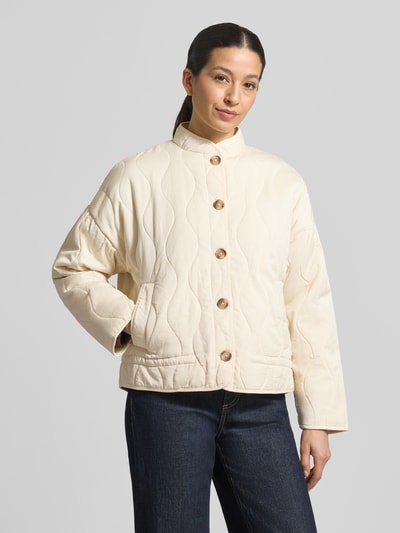 Frauenmodel trägt Steppjacke aus Lyocell-Baumwoll-Mix mit Stehkragen von Jake*s Casual, cremefarben, Knopfleiste, Eingrifftaschen, Regular Fit, glatte und gesteppte Struktur, Ganzkörperansicht von vorne.