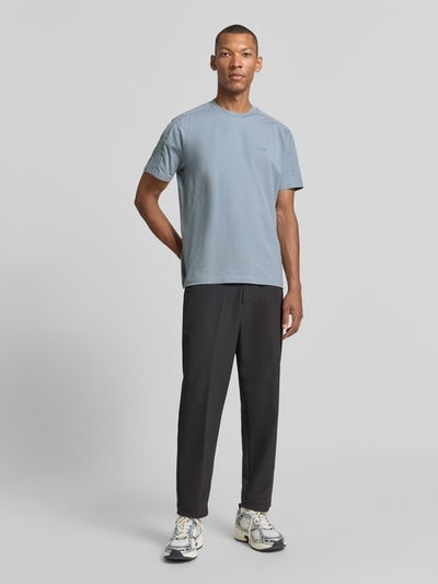 Mannenmodel draagt lichtblauw Regular Fit T-Shirt aus Baumwoll-Mix model 'TS_Union Tape' van BOSS Green, zwarte broek, sneakers, Ganzkörperansicht van voren.