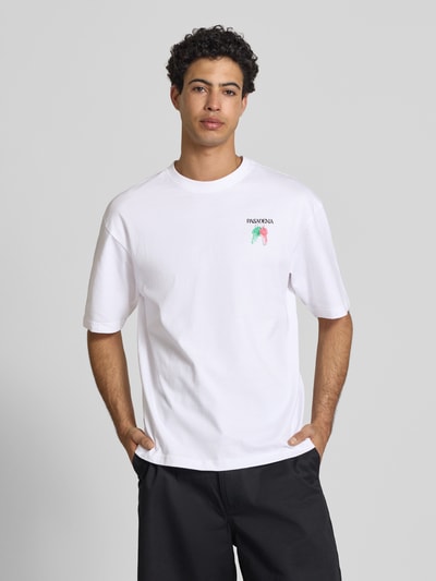 Męski model nosi Boxy Fit T-Shirt aus reiner Baumwolle Modell 'FRED ESCAPE' von Only & Sons, biała uniwersalna koszulka z nadrukiem z jerseyu, okrągły dekolt, krótkie rękawy, Ganzkörperansicht von vorne.