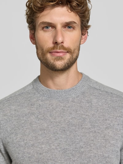 Männermodel trägt Regular Fit Strickpullover aus reinem Kaschmir von FTC Cashmere in hellgrau, weiche Textur, Nahaufnahme Oberkörper.