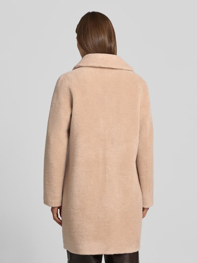 Frauenmodel trägt Wendemantel in Woll-Lammfell-Optik Modell 'VENUS' von OAKWOOD, Beige, lockere Passform, Reverskragen, Eingrifftaschen, Ganzkörperansicht Rückansicht. Rückenlänge 89 cm, Schulterbreite 44 cm, Brustweite 50 cm, Ärmellänge 62 cm.