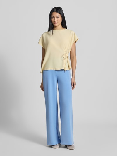 Frauenmodel trägt Sweatpants mit Stretch-Anteil von Milano Italy im Modal-Elasthan-Mix, hellblau mit weitem Bein, lockerer Passform, elastischem Logo-Bund, Eingriff- und angedeuteten Gesäßtaschen, Ganzkörperansicht von vorne.