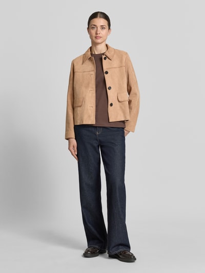 Frauenmodel trägt Lederjacke aus Ziegenvelours mit Pattentaschen von More & More in Beige mit Umlegekragen, Knopfleiste, Regular-Fit, Ganzkörperansicht von vorne. Rückenlänge bei Größe 36: 54 cm, Schulterbreite: 37 cm, Brustweite: 51 cm, Ärmellänge: 60 cm.