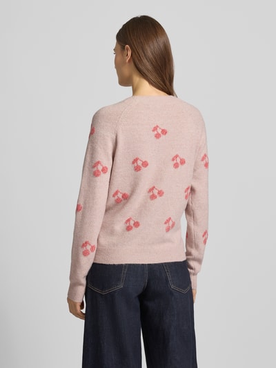 Vrouwenmodel draagt Regular Fit Strickpullover mit Intarsien Modell 'DOFFY INTARSIA' van Vero Moda, lichtroze met rood patroon, gebreid, ronde hals, ribboorden, label stitching, allover-motief, unicolor, lange mouwen. Volledige lichaamsweergave achteraan.