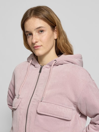 Frauenmodel trägt Regular Fit Bomberjacke mit Kapuze Modell 'SUVA' von Only aus rosafarbenem Cord, gestreift, Nahaufnahme Oberkörper.