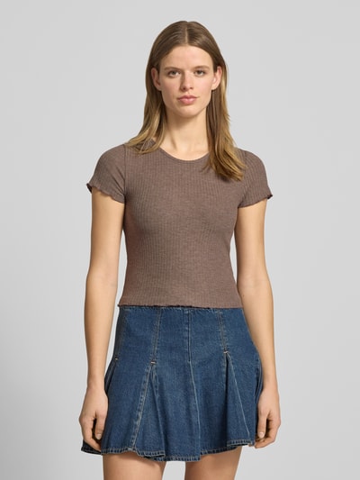 Kobiece modelka nosi damski t-shirt w jednolitym kolorze, krój slim fit, okrągły dekolt, krótki rękaw, frędzlowe zakończenia, prążkowana faktura, model 'EMMA' od ONLY, wykończenie materiału: prążkowana faktura. Ganzkörperansicht von vorne.