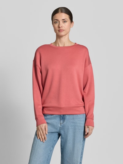 Kobieta prezentuje bluzę Sweatshirt mit Rundhalsausschnitt Modell 'Ima' od MSCH Copenhagen, mieszanka wiskozy z dodatkiem streczu, krój regular fit, okrągły dekolt, opuszczone ramiona, elastyczne wykończenia, kolor różowy, gładka faktura, widok całej sylwetki z przodu.