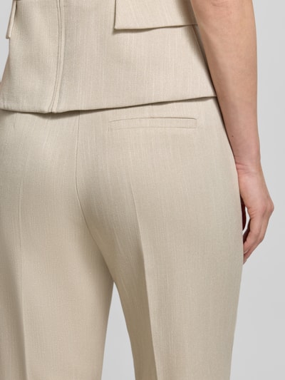 Frauenmodel trägt Hose aus Viskose-Mix mit Bügelfalten von comma in Beige mit Gesäßtasche, glatter Stoff, Nahaufnahme Rückansicht.