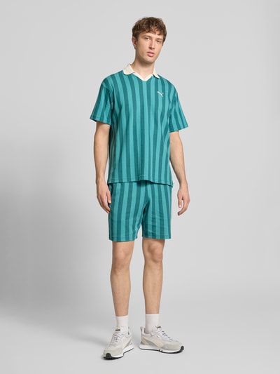 Męski model nosi szorty z elastycznym pasem od PUMA PERFORMANCE, mieszanka bawełny, krój regular fit, wyhaftowane logo, tunel, szerokość w rozmiarze M 39 cm, długość wewnętrzna nogawki w rozmiarze M 20 cm, zdjęcie całej sylwetki z przodu.