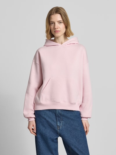 Frauenmodel trägt Regular Fit Hoodie mit Känguru-Tasche Modell 'Iconic' von Gina Tricot in Hellrosa, Baumwoll-Mix, elastische Abschlüsse, Damen Hoodie, Ganzkörperansicht von vorne.