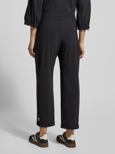 Vrouwenmodel draagt Stoffen broek met elastische band van Marc Cain, materiaalmix met stretch, los model, steekzakken. Volledige achteraanzicht.