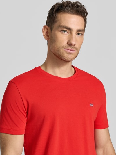 Männermodel trägt T-Shirt aus Baumwolle mit Rundhalsausschnitt von Christian Berg Men in Rot, Regular-Fit, Label-Detail, Nahaufnahme Oberkörper. Reine Baumwolle, Rückenlänge bei Größe M 71 cm.