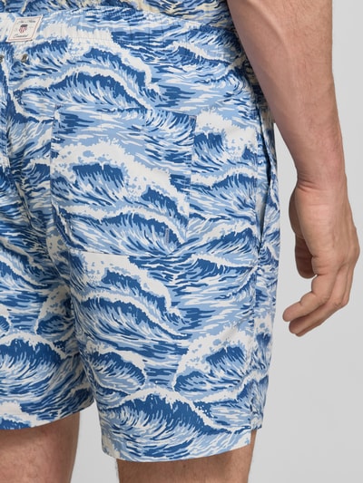 Mannenmodel draagt Straight Fit Badehose mit elastischem Bund van Gant met blauwe allover-motiefprint, elastische taille, detailopname heup/achterkant