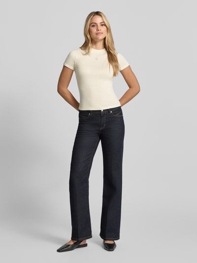 Vrouwenmodel draagt T-Shirt uit viscosemix model 'LICIA' van GUESS, slim fit, strassteentjeslogo, crèmekleur, volledig frontaal lichaamsbeeld.