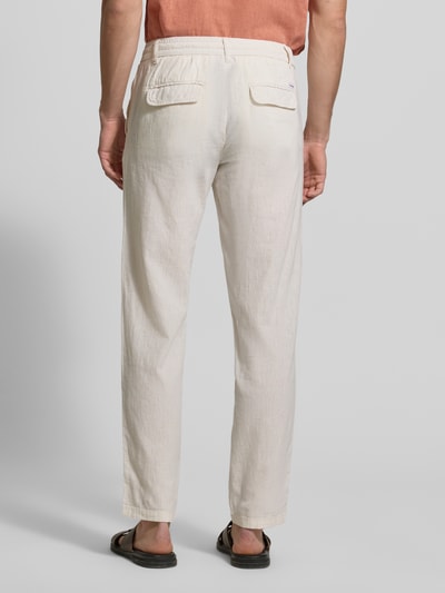 Męski model nosi Hose aus Leinen-Baumwoll-Mix mit elastischem Bund von Lindbergh, kolor ecru, krój regular fit, kieszenie z przodu, szerokość w rozmiarze M: 40 cm, długość nogawki od wewnątrz: 79 cm, zdjęcie całej sylwetki z tyłu.