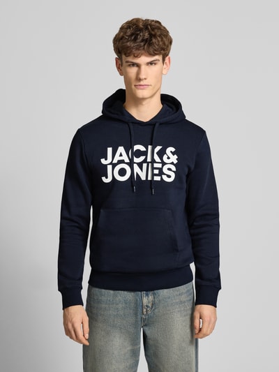 Männermodel trägt Hoodie mit Label-Print und Känguru-Tasche von Jack & Jones, dunkelblau, Baumwoll-Mix, Regular Fit, Ganzkörperansicht von vorne.