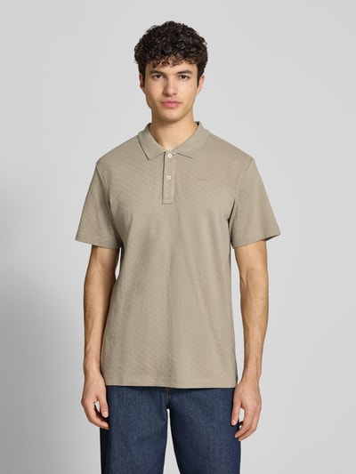 Męski model nosi Regular Fit Poloshirt mit Logo od G-Star Raw, beżowa bawełna, krój regular fit, z logo i zapięciem na guziki, widok całej sylwetki z przodu.