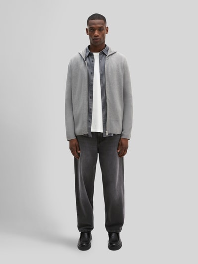 Männermodel trägt Regular Fit Pullover aus reiner Baumwolle von Marc O'Polo in Hellgrau, kombiniert mit dunkler Jeans, Ganzkörperansicht von vorne. Herren Pullover von Marc O'Polo.