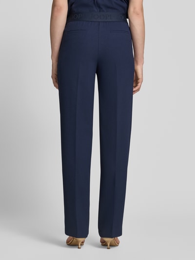 Frauenmodel trägt dunkelblaue Straight Fit Stoffhose mit Ziernaht und elastischem Bund, Modell 'Paulien' von JOOP!, Ganzkörperansicht Rückansicht.