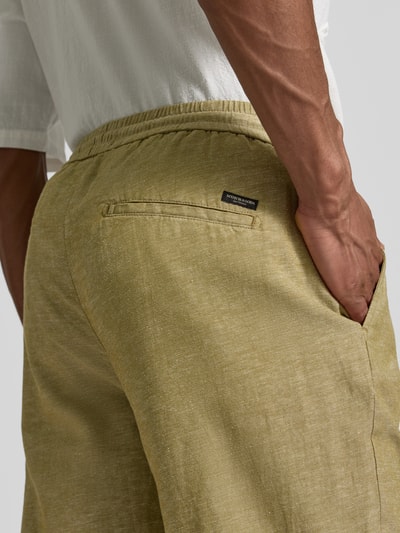 Männermodel trägt Hose mit Leinen-Anteil und französischen Eingrifftaschen von Scotch & Soda, Baumwoll-Mix in Beige, Detailaufnahme Rückansicht.