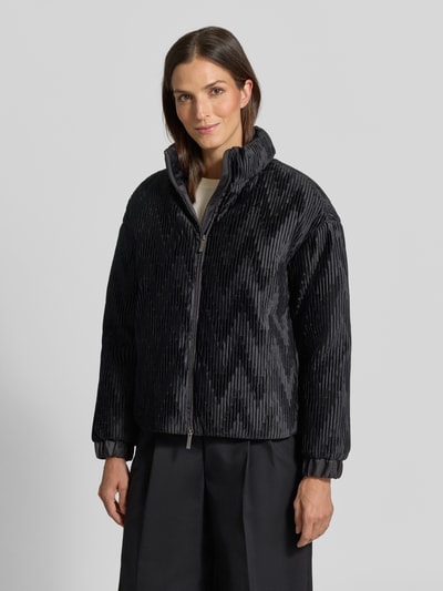 Frauenmodel trägt Jacke mit Zweiwege-Reißverschluss von Emporio Armani in Schwarz, Ripp-Optik, hoher Stehkragen, elastische Ärmelabschlüsse, gerade Passform, Ganzkörperansicht von vorne.