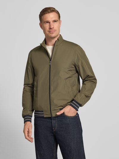 Männermodel trägt olivgrünen Blouson mit Stehkragen und Reißverschluss von Geox, Regular-Fit, Eingrifftaschen, Ganzkörperansicht von vorne. Rückenlänge bei Größe M: 68 cm, Schulterbreite: 46 cm, Brustweite: 56 cm, Ärmellänge: 68 cm.