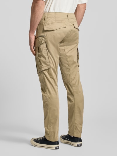 Mężczyznamodel nosi Regular Tapered Fit Spodnie cargo z kieszenią zapinaną na zamek błyskawiczny od G-Star RAW, mieszanka bawełny i elastanu, model Rovic, szlufki na pasek, 5 kieszeni, kolor beżowy, widok całej sylwetki z tyłu.